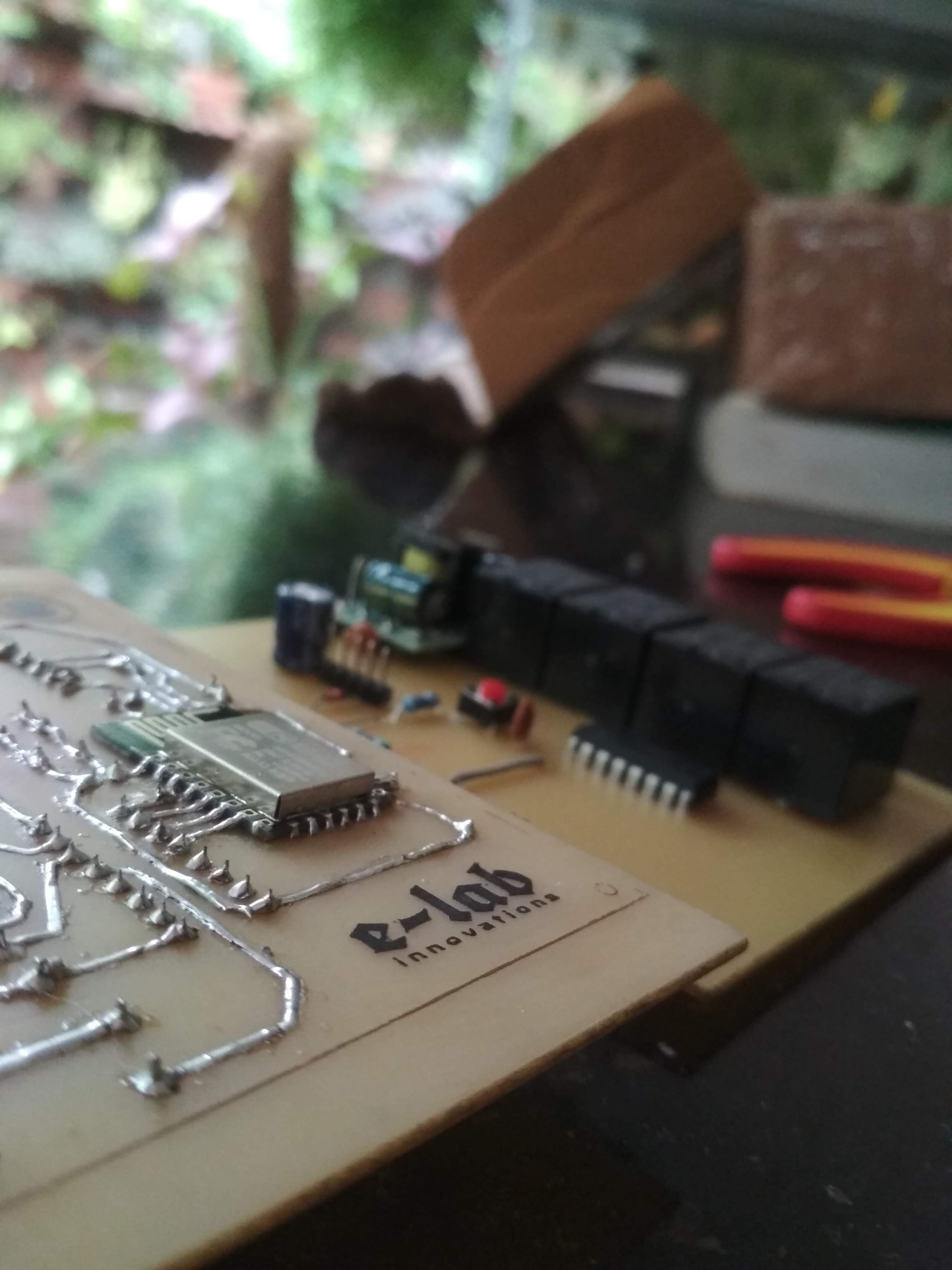 Close-up of a custom ESP-12-based home automation board with relays and through-hole soldering.